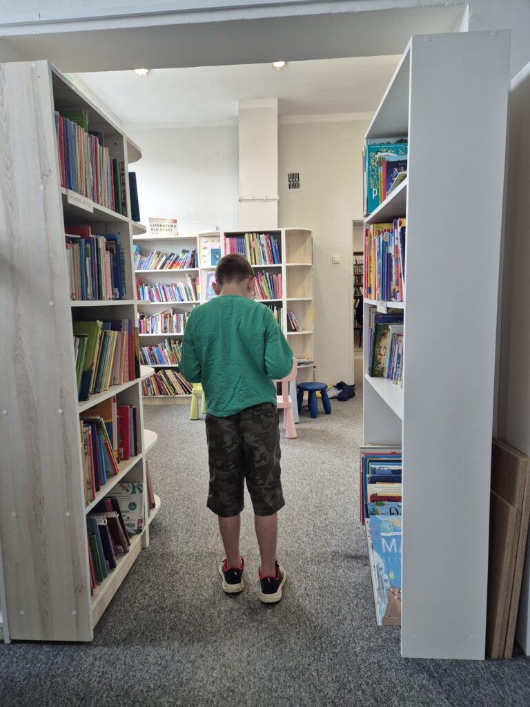 chłopiec stojący między regałami z książkami