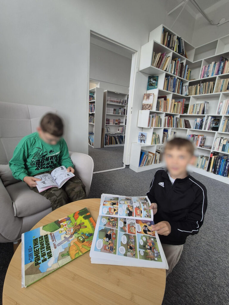 dwóch chłopców czytających komiksy przy stoliku
