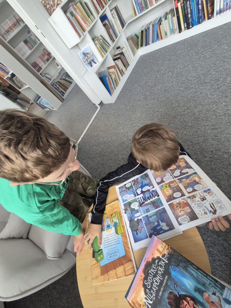 dwóch chłopców czytających komiksy przy stoliku